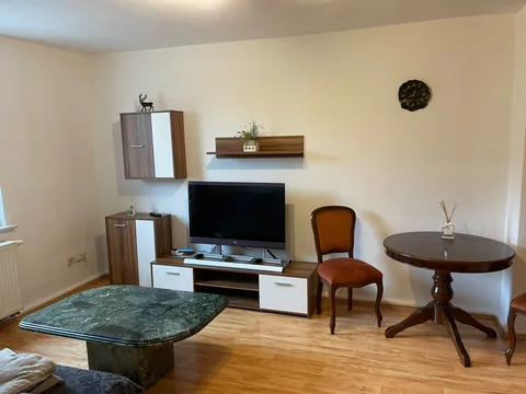 Wohnzimmer mit Fernseher und kleinem Tisch
